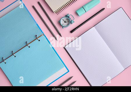 Des carnets ouverts et des fournitures scolaires des accessoires sur fond pastel. Banque D'Images