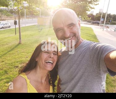 Un selfie d'un heureux couple d'âge moyen avec des sourires joyeux dans un joli parc par une journée ensoleillée Banque D'Images