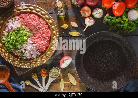 Préparation pour une délicieuse recette du Moyen-Orient. Viande hachée avec des ingrédients frais prêts à cuire. Vue de dessus avec espace de copie. Banque D'Images