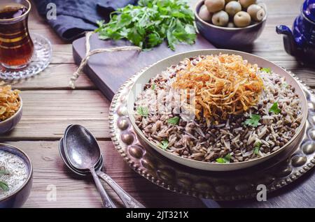 Cuisine arabe ; plat oriental traditionnel « Mujadara » ou « Mudarara ». Il se compose de lentilles noires cuites, de riz et d'oignons frits croustillants. Banque D'Images