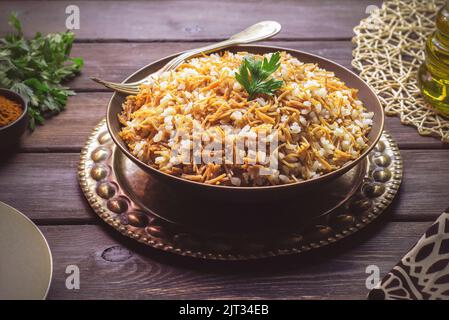 Cuisine arabe ; plat oriental égyptien « riz avec vermicelles » placé sur fond rustique en bois. Banque D'Images