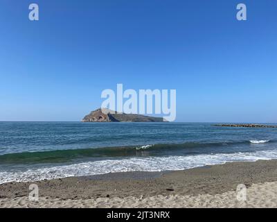 Une belle vue sur une mer bleue calme avec de faibles marées et une colline sous un ciel clair à la plage d'Agia Marina en Crète, Grèce Banque D'Images