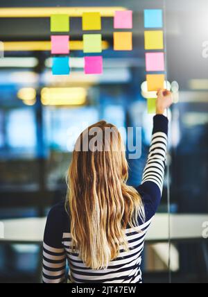 Aucune idée n'est laissée pour compte. Photo d'une femme ayant une séance de remue-méninges avec des notes adhésives au travail. Banque D'Images