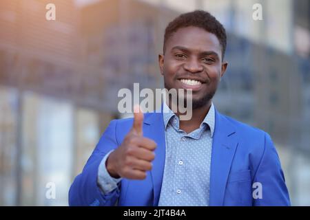 L'homme d'affaires afro-américain dans un blazer bleu montre le pouce vers le haut Banque D'Images