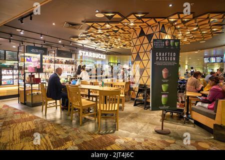 SINGAPOUR - VERS JANVIER 2020 : les gens sont assis à Starbucks à l'aéroport de Changi, un important aéroport civil qui dessert Singapour. Banque D'Images