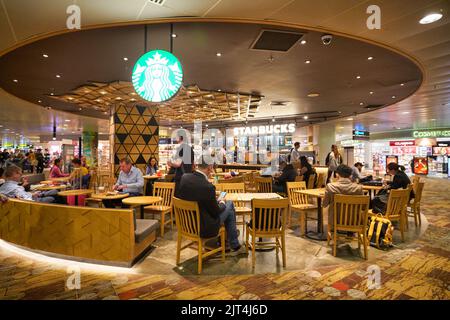 SINGAPOUR - VERS JANVIER 2020 : les gens s'assoient au Starbucks Coffee de l'aéroport Changi de Singapour. Banque D'Images