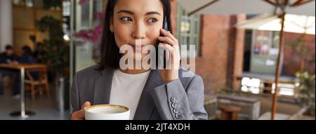 Jeune femme d'affaires asiatique parlant sur un téléphone portable debout à l'extérieur, bannière. Banque D'Images