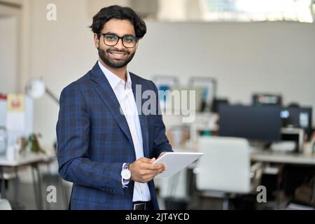 Jeune homme indien souriant, Manager portant un costume tenant une tablette, portrait. Banque D'Images