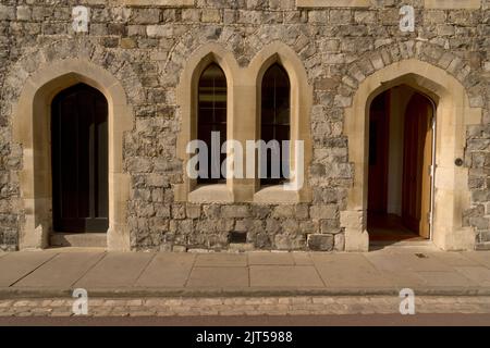 Détail du mur du château médiéval fait de briques de pierre massives et deux portes en bois et des fenêtres de lancet à utiliser comme arrière-plan Banque D'Images