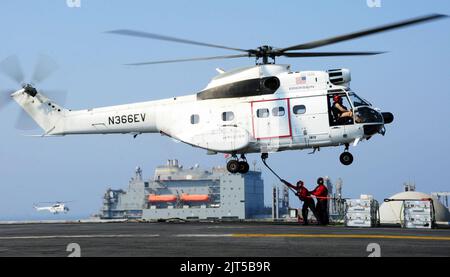 Marins américains à bord du porte-avions USS George H.W. Bush (CVN 77) attachez un crochet de chargement à un hélicoptère Puma sa-330J du Commandement de la sécurité militaire lors d'un réapprovisionnement en mer avec la cargaison sèche et les munitions 140827 Banque D'Images