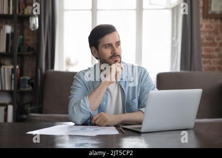 Homme d'affaires freelance et attentionné assis à un ordinateur portable dans un bureau à domicile Banque D'Images