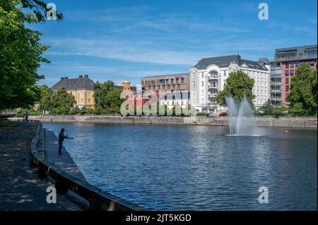 Homme pêchant sur le front de mer de Norrkoping dans le ruisseau Motala début août 2022. Norrkoping est une ville industrielle historique de Suède. Banque D'Images