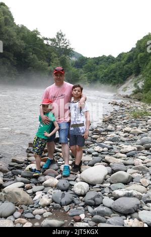 Père avec ses fils sur la rive de la rivière Belaya, Adygea Banque D'Images