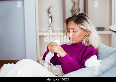 Jour de maladie à la maison. La femme blonde a un rhume liquide et commun. Toussez. Gros plan de la belle jeune femme attrapée rhume ou grippe maladie. Portrait de GI malsain Banque D'Images