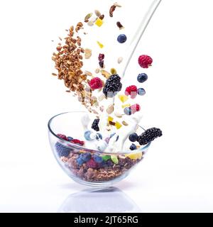 Lévitation de granola et de baies sur une plaque de verre. Le lait à la vapeur et une variété de baies. Baies et lait dans l'air. Banque D'Images