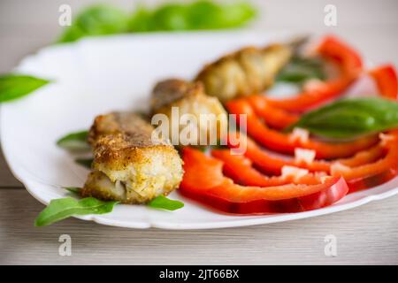 Morceaux de merlu frits dans une assiette de poivre sur une table en bois Banque D'Images