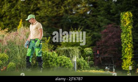 Jardinier caucasien professionnel dans son 40s intérieur moderne de jardin résidentiel. Tâche d'entretien de cour arrière Banque D'Images