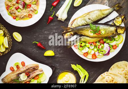 Cuisine méditerranéenne, poisson fumé au hareng servi avec de l'oignon vert, du citron, du piment, de la laitue, des épices, pain pita et sauce tahini. Banque D'Images