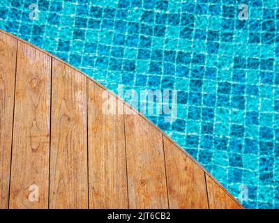 Vue de dessus d'une table en bois vide ou d'un plancher de terrasse forme incurvée devant l'arrière-plan flou de carreaux de mosaïque bleu motif de grille dans la piscine. Banque D'Images