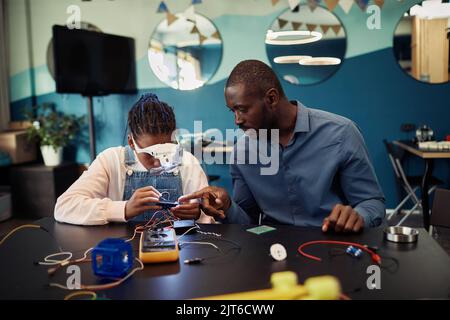 Portrait de la jeune fille noire robot de construction dans la classe d'ingénierie avec l'aide d'enseignant de sexe masculin Banque D'Images