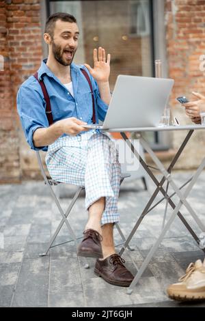 Un homme d'affaires élégant a une conversation en ligne sur ordinateur portable au café Banque D'Images