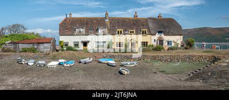 A marée basse, une rangée de petits bateaux se trouve sur le bardeau en police des petites maisons de Porlock Weir dans le Somerset. Banque D'Images