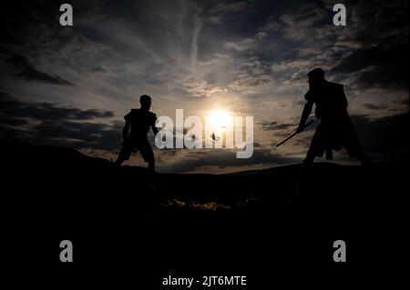 Épée d'art martial combat silhouettes au coucher du soleil Banque D'Images