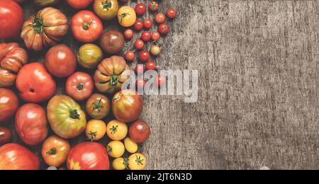 Tomates biologiques multicolores non traitées sur une table sombre, vue du dessus avec espace pour les copies Banque D'Images