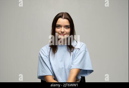 Portrait de jeune belle mignonne gaie femme en t-shirt beige souriant regardant l'appareil photo sur fond bleu. Banque D'Images