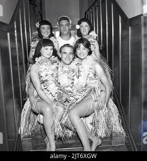 1965, historique, production théâtrale du Pacifique Sud, coulisses sur un escalier, les artistes se réunissent pour une photo de groupe, deux heureux 'ailors' avec des filles en jupes de gazon, Fife, Écosse, Royaume-Uni. South Pacific est une comédie musicale écrite par le partenariat à succès de Rodgers et Hammerstein, basée sur le livre Tales of the South Pacific et qui a été créée sur Broadway en 1949. Banque D'Images