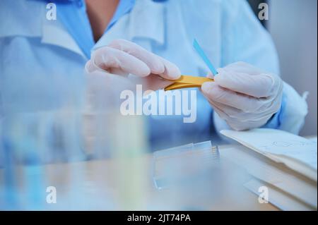 Détails : les mains du scientifique tiennent une bande indicatrice pH pour mesurer l'alcalinité et l'acidité des substances en laboratoire Banque D'Images