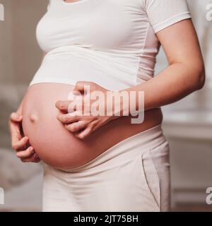 Femme enceinte ventre, salon à la maison Banque D'Images