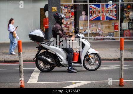 LONDRES - 20 mai 2022 : un homme dans un casque sur un scooter blanc s'est arrêté sur la route Banque D'Images