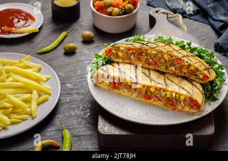 Cuisine arabe; cuisine égyptienne traditionnelle 'Hawawshi'. C'est du pain égyptien plat farci de viande hachée et épicé avec des oignons, des poivrons et des piments. Banque D'Images