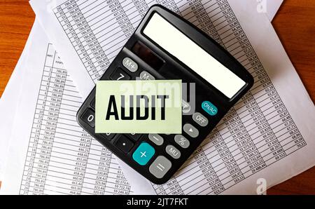 Le mot AUDIT est écrit sur un autocollant qui se trouve sur une calculatrice et des documents avec des calculs. Gros plan Banque D'Images