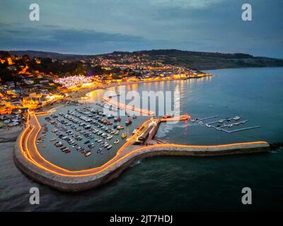 Lyme Regis, Dorset, Royaume-Uni. 28th août 2022. Vue de l'air que des milliers de bougies de thé éclairent les murs historiques du port de Cobb à Lyme Regis dans Dorset au crépuscule. Il y a aussi une couronne géante illuminée sur la plage pour commémorer le Jubilé de platine de la Reine. Cet événement spectaculaire où les gens commanditent une bougie en mémoire d'un être cher est de recueillir de l'argent pour les projets de jeunesse de Lyme Regis, la Croix-Rouge britannique et cancer Research UK. Crédit photo : Graham Hunt/Alamy Live News Banque D'Images