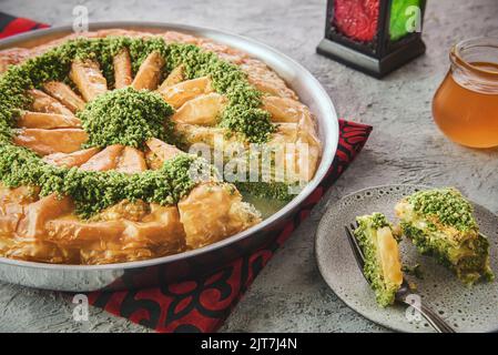 Dessert traditionnel du Moyen-Orient « Baklava » ou « Baklawa ». Servi dans une plaque de cuisson et recouvert de délicieux pistaches écrasées. Banque D'Images