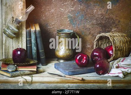 Classique encore vie avec des pommes rouges fraîches placées avec un pot antique et de vieux livres sur fond rustique en bois. Banque D'Images