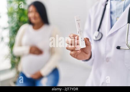 Jeune couple latin médecin et patient ayant une consultation médicale tenant le test d'antigène à la clinique Banque D'Images