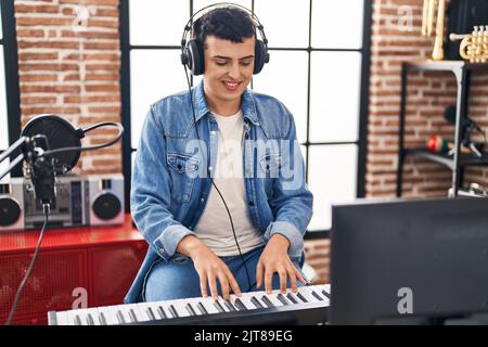 Jeune homme non binaire musicien jouant un clavier de piano dans un studio de musique Banque D'Images