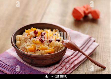 Marrige de millet avec potiron dans un bol en argile avec une cuillère en bois sur fond en bois Banque D'Images
