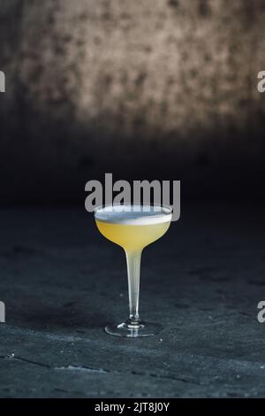 royal Hawaiian jaune ananas cocktail avec mousse dans tige creuse coupé verre avec fond en béton foncé Banque D'Images