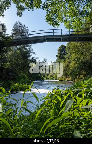 Vue de sous le pont de polluants en mousse blanche tournoyant sur la surface de l'eau flottant sur la rivière Caima, Palmaz - Oliveira de Azemeis - Portugal Banque D'Images