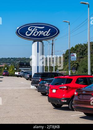 Les voitures d'occasion à vendre sont alignées dans un concessionnaire Ford avec son panneau au-dessus d'elles lors d'une journée ensoleillée d'été Banque D'Images