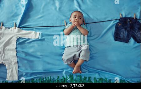 Un bon départ dans la vie. Photo conceptuelle d'un adorable bébé garçon accroché à une ligne de vêtements Make Believe. Banque D'Images