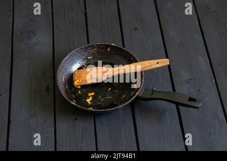 une poêle avec les restes de nourriture et une spatule en bois après la friture est sur la table dans la cuisine, une poêle sale est sur la table Banque D'Images