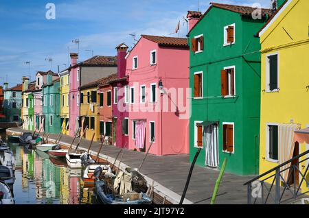 Des bateaux flottent sur un canal d'eau calme près de maisons multicolores contre le ciel bleu le jour ensoleillé sur la rue de l'île de Burano en Italie Banque D'Images