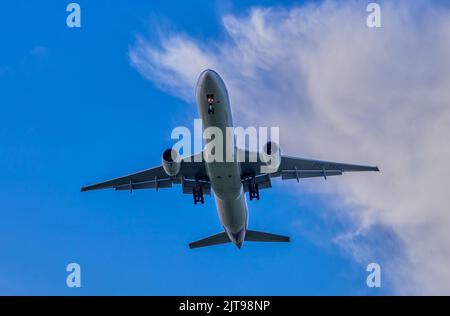 Un avion dans un ciel bleu avec des nuages blancs. Banque D'Images