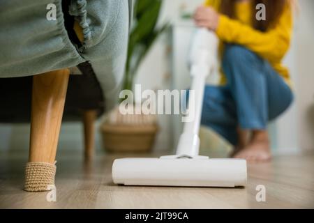 Bonne jeune femme asiatique avec accumulateur aspirateur à la maison dans le salon, femme de ménage nettoyage de poussière sol sous canapé ou meubles avec vacu Banque D'Images