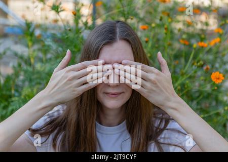 Une femme couvre ses yeux avec ses mains Banque D'Images